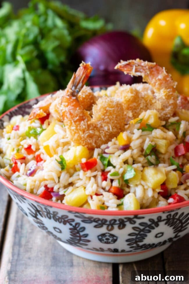Confetti Caribbean Rice served in a bowl, topped with coconut shrimp and fresh cilantro.