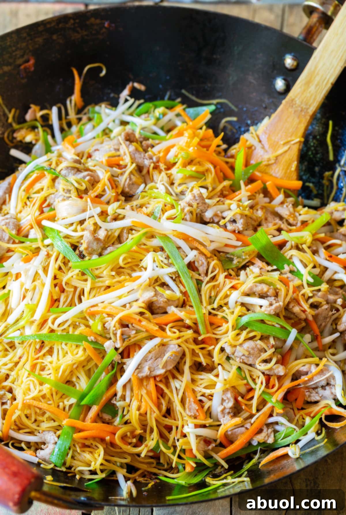 Classic Cantonese Pork Lo Mein 3 Pork Lo Mein cooking in a large wok, showcasing the fresh ingredients and noodles being stir-fried.