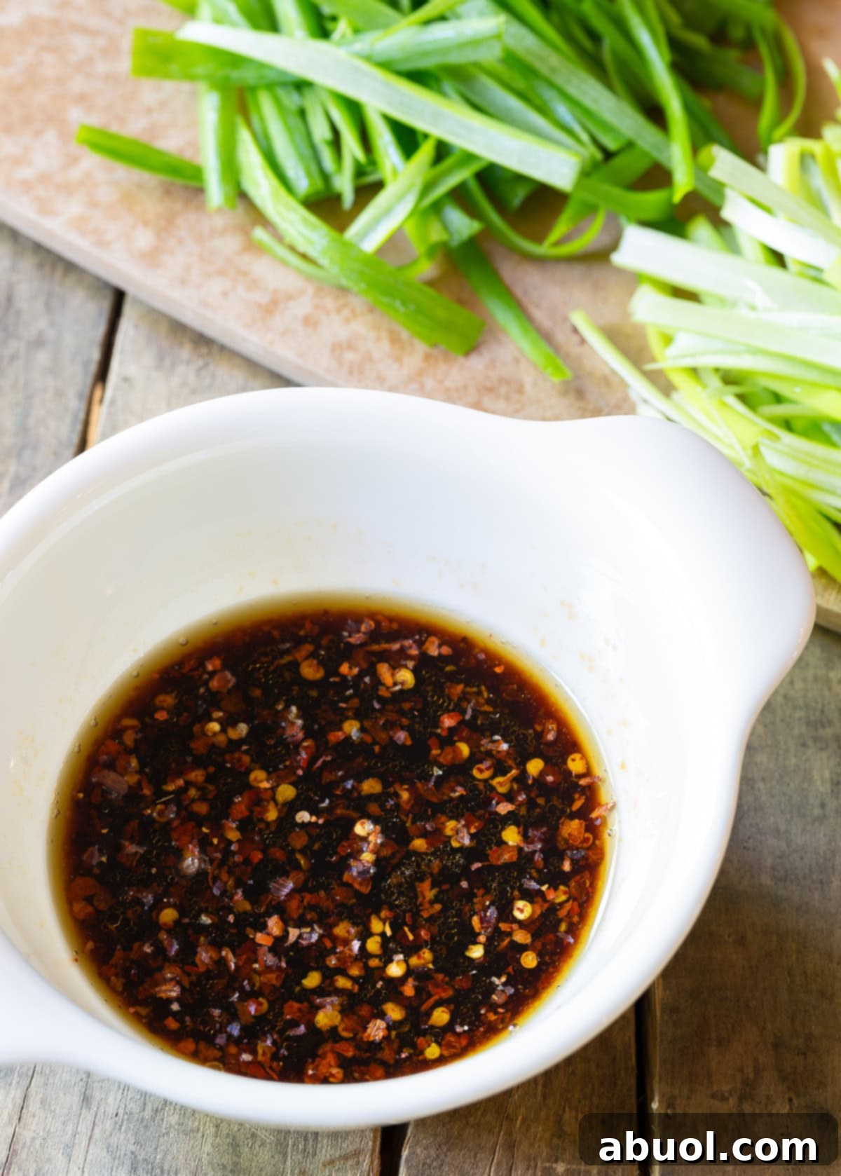 Classic Cantonese Pork Lo Mein 5 A small white bowl filled with the perfectly blended savory and spicy sauce for Pork Lo Mein.