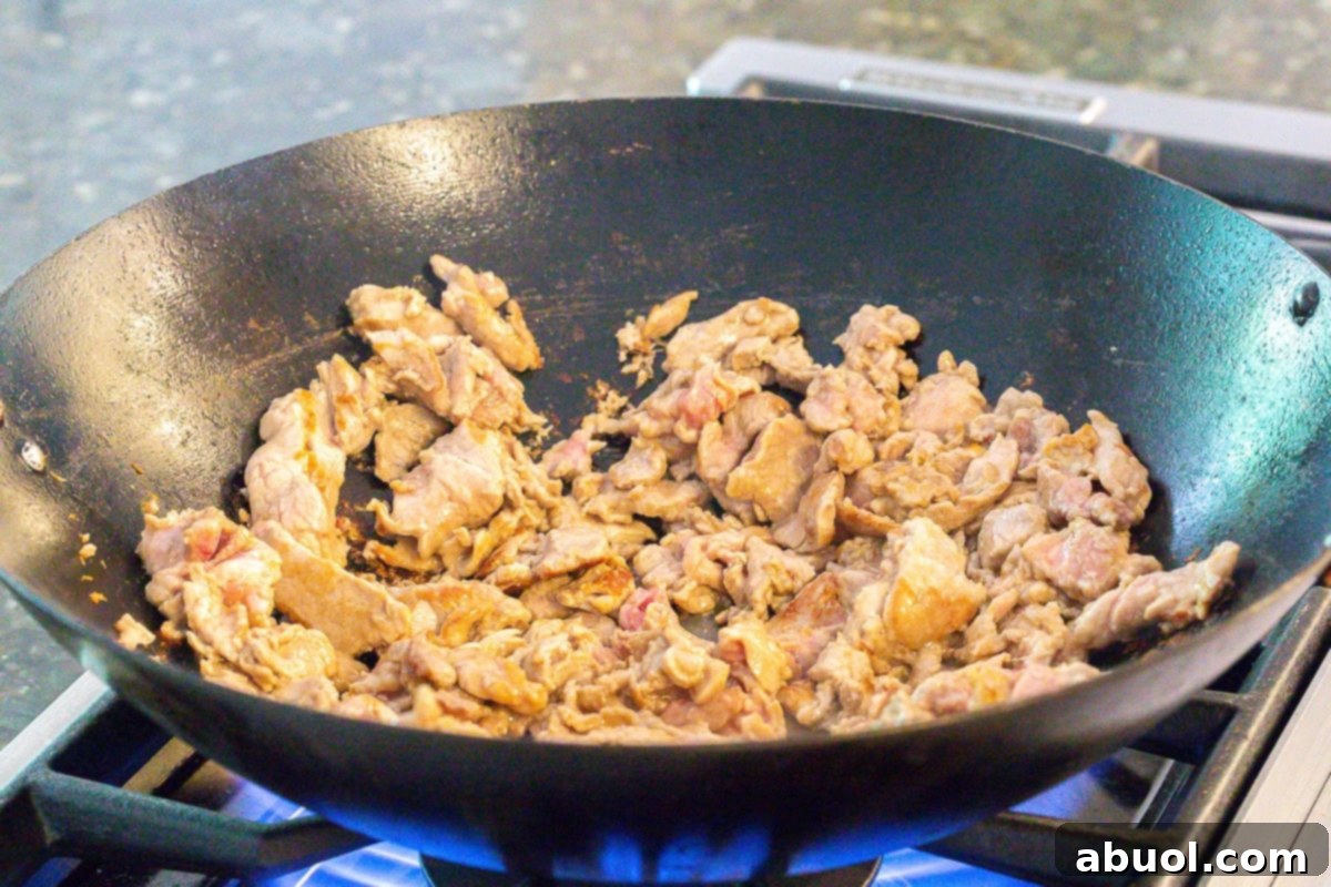 Classic Cantonese Pork Lo Mein 6 Thinly sliced pork searing in a hot wok, ready to be incorporated into Cantonese Noodles.