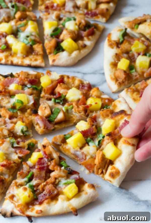 Close-up shot of a hand gracefully removing a delectable slice of Teriyaki Chicken Pizza from a sizzling hot grill.