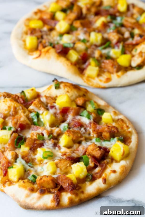 A vibrant close-up of a perfectly grilled Teriyaki Pizza, generously topped with tender chicken and glistening pineapple pieces, ready to be served.