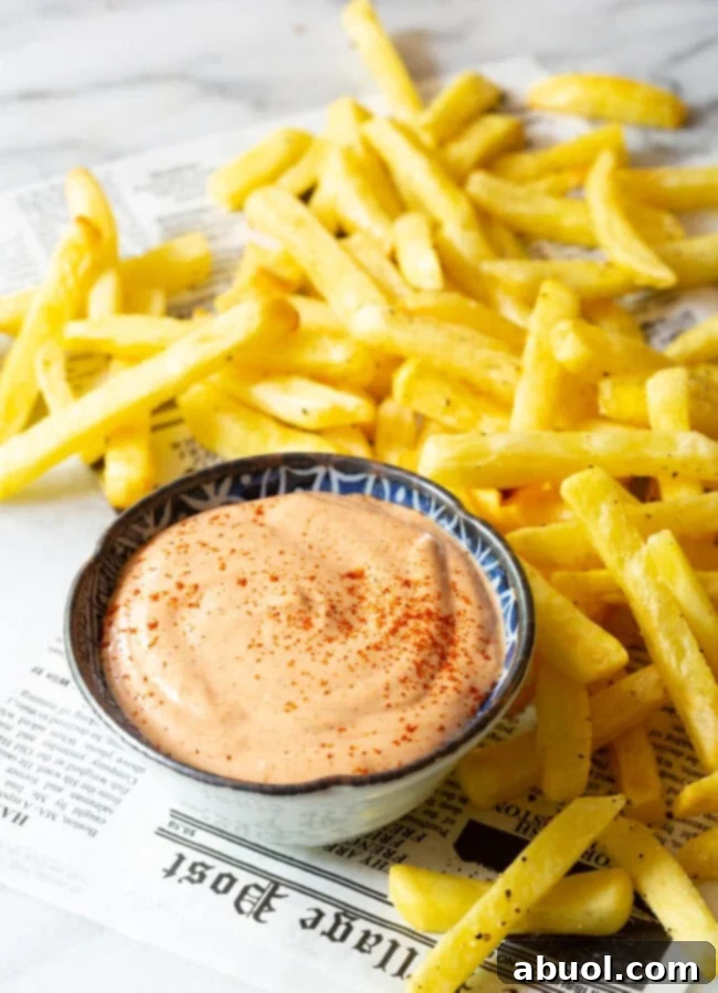 top view of southern dip with some french fries next to it on a newspaper. 