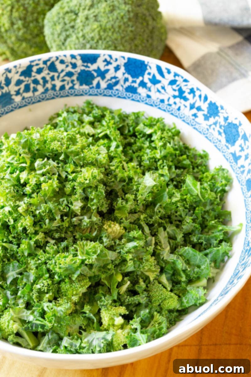 Various colorful ingredients for broccoli salad, including chopped broccoli, dried cherries, and shredded carrots, arranged on a cutting board.
