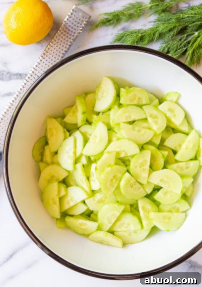 top view of thinly sliced and halved English cucumbers in a large mixing bowl.