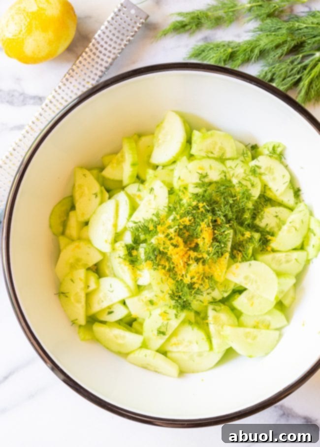Close up of all ingredients for creamy cucumber salad in a bowl before mixing.