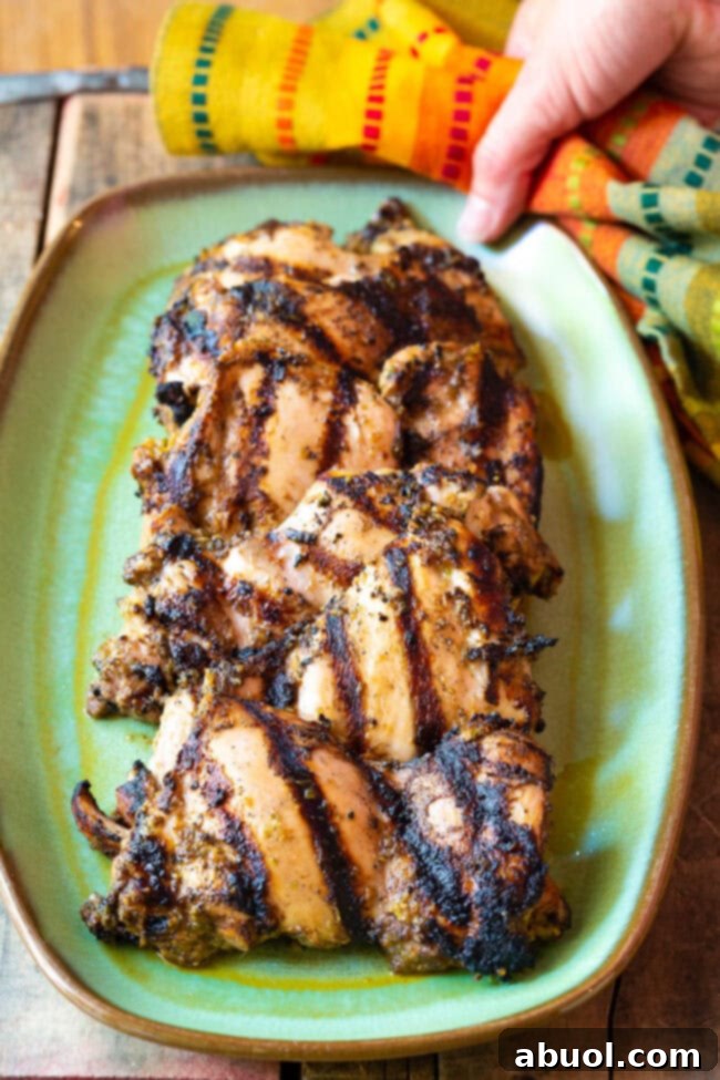 Grilled Jamaican Jerk Chicken Thighs on a platter, showcasing the rich marinade and perfectly cooked meat.
