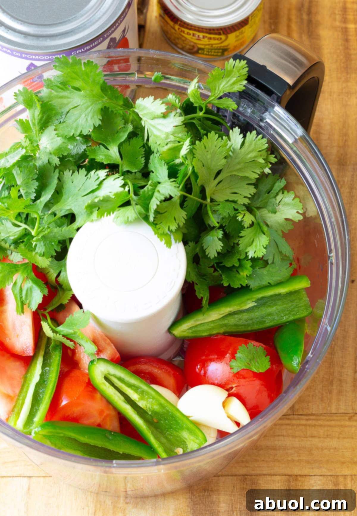 Fresh tomatoes, onions, garlic, and jalapeños being processed in a food processor, capturing the initial stage of making a chunky homemade salsa.