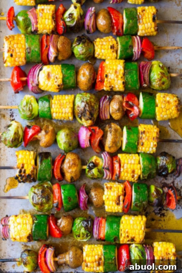 An overhead shot of multiple grilled vegetable kabobs arranged on a white platter, showcasing the beautiful char and colors.