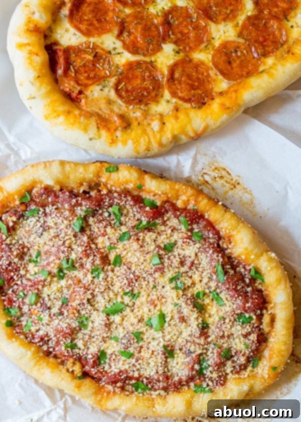 A top down view of two slow cooker deep dish pizzas resting on a piece of white parchment paper, showcasing their thick crust and generous toppings.