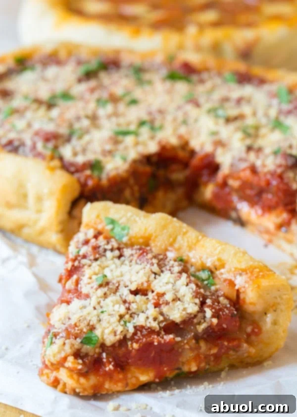 A single, delectable slice of slow cooker deep dish pizza, showcasing its rich layers of cheese, sauce, and crumbled sausage, set against the backdrop of the remaining pizza.