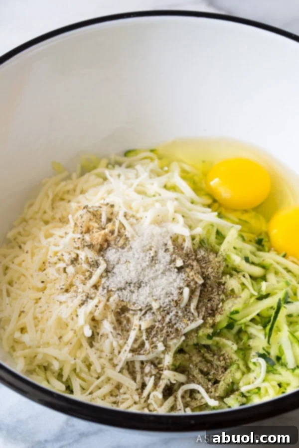 All the fresh ingredients for healthy baked zucchini tots laid out and combined in a mixing bowl, ready for shaping and baking.