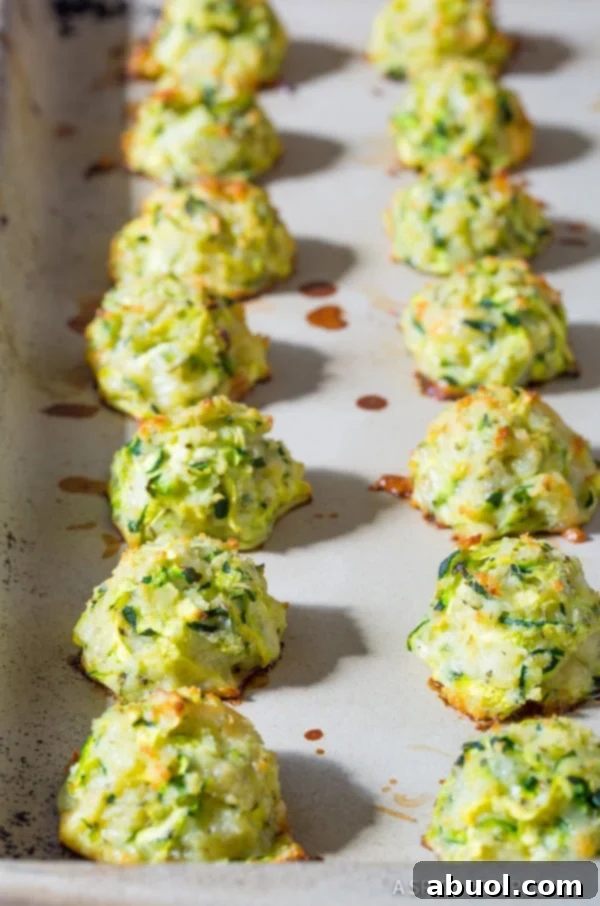 Golden brown and crispy zucchini tots resting on a baking sheet, freshly baked and ready to be served as a healthy and delicious side.