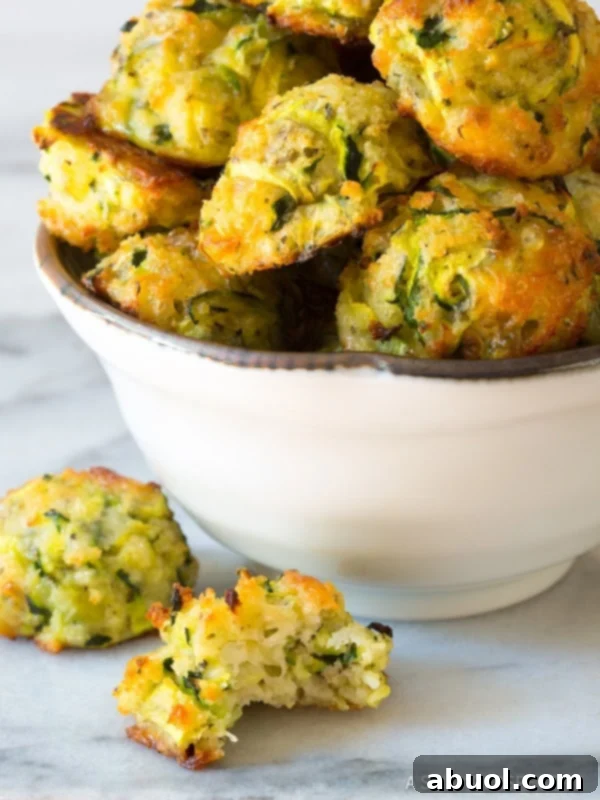 A close-up shot of baked zucchini tots served in a rustic bowl, with one tot partially bitten, showcasing its inviting texture.
