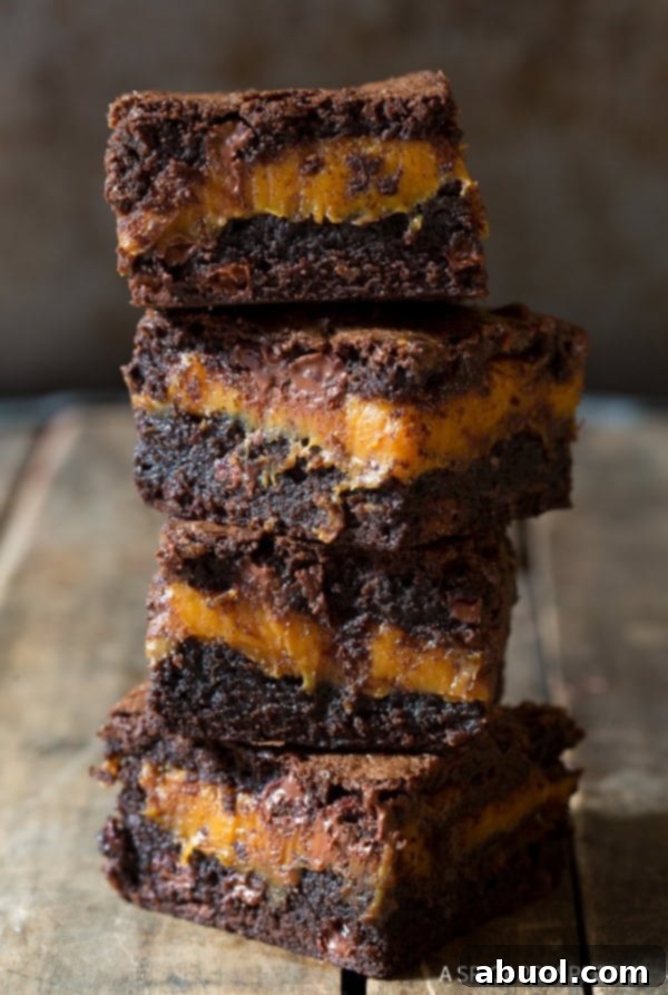 Gooey Caramel Brownie Recipe cut into squares and stacked on top of each other, showcasing the luscious caramel layer.