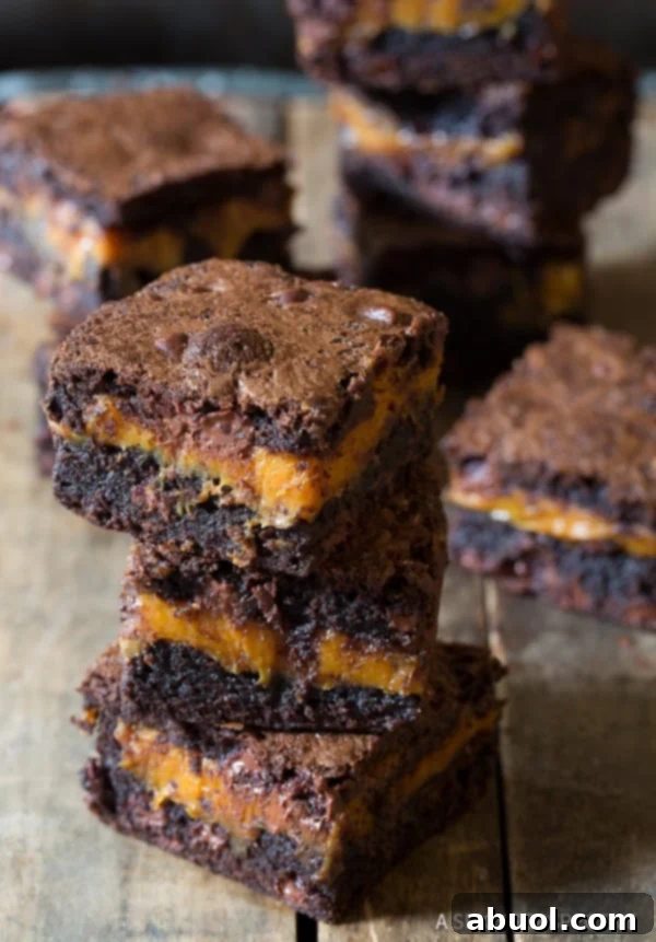 Best Gooey Caramel Brownie Recipe on counter, stacked neatly in the front and the back, ready to be enjoyed.