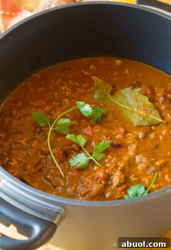 A large pot of healthy gluten-free pumpkin chili, garnished with fresh cilantro and bay leaves for a beautiful presentation.