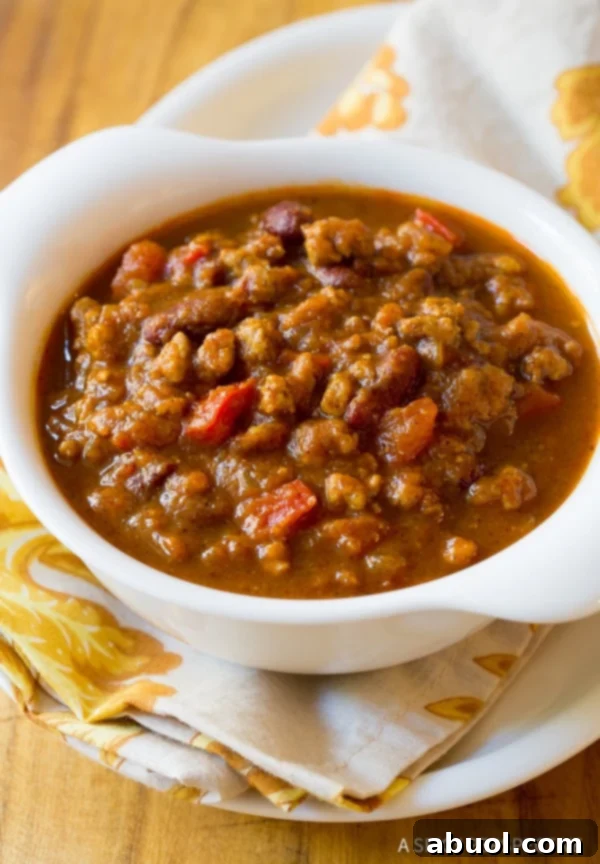 A close-up shot of a bowl of healthy gluten-free pumpkin chili, topped with fresh cilantro and a dollop of sour cream.