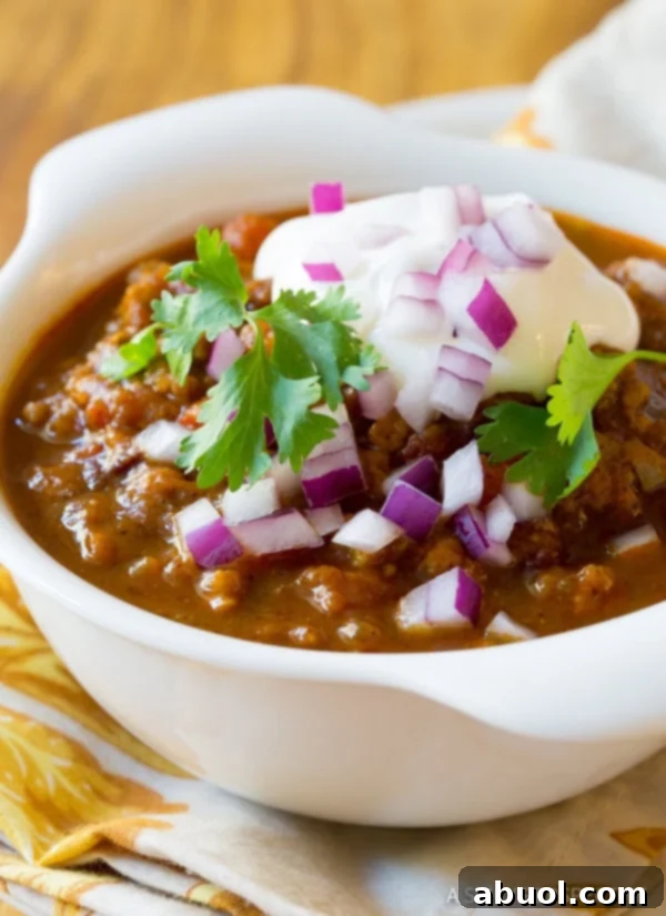 A vibrant bowl of pumpkin chili, generously topped with an array of fresh ingredients like cilantro, sour cream, and red onions, capturing the essence of a perfect fall meal.