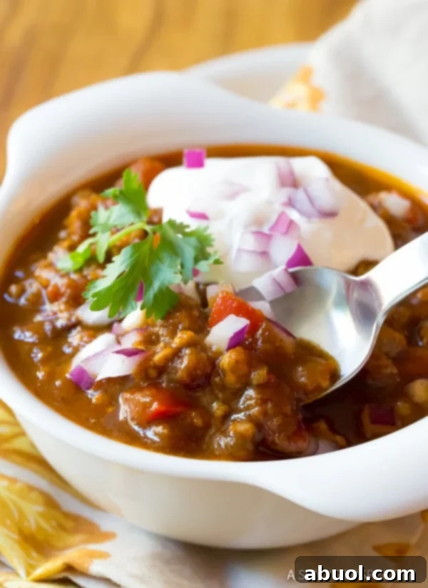 A ceramic bowl of pumpkin chili with a silver spoon resting inside, ready to be enjoyed.