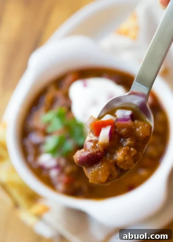 A delicious spoonful of pumpkin chili being lifted from a bowl, showcasing its rich texture and vibrant color.
