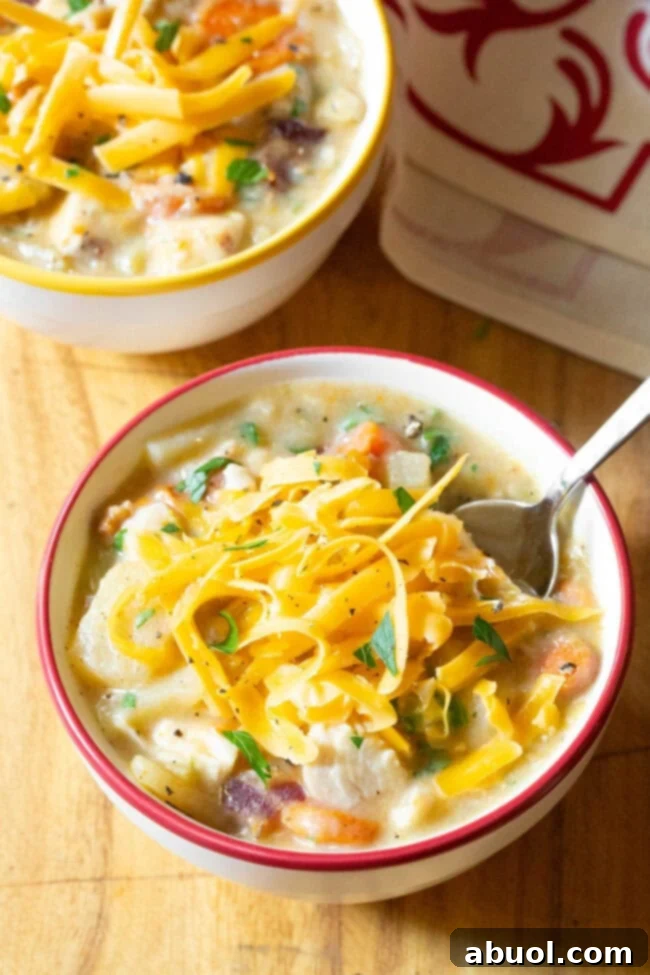 Two bowls of chicken potato soup topped with shredded cheese.