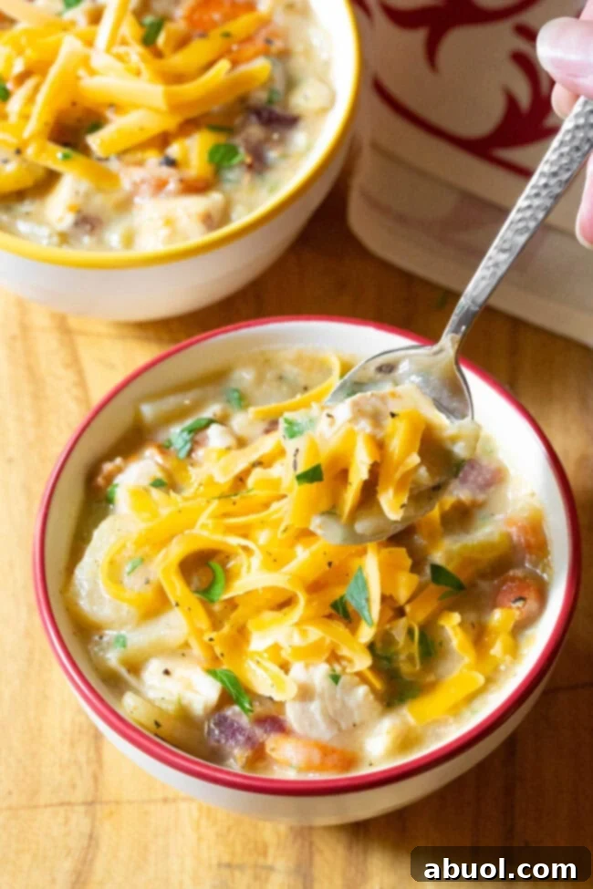 Crockpot Potato soup in a bowl with a hand holding a spoon scooping up a bite.