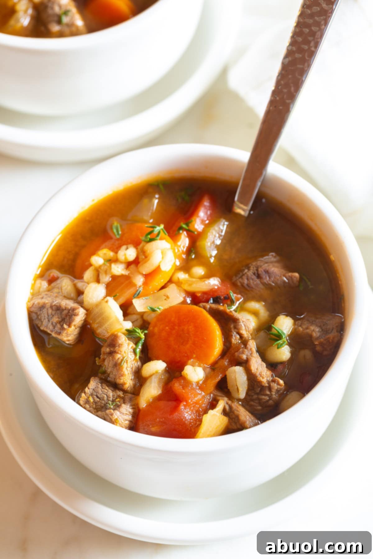 Close-up of hearty beef and barley soup in a bowl with visible chunks of beef, barley, and vegetables