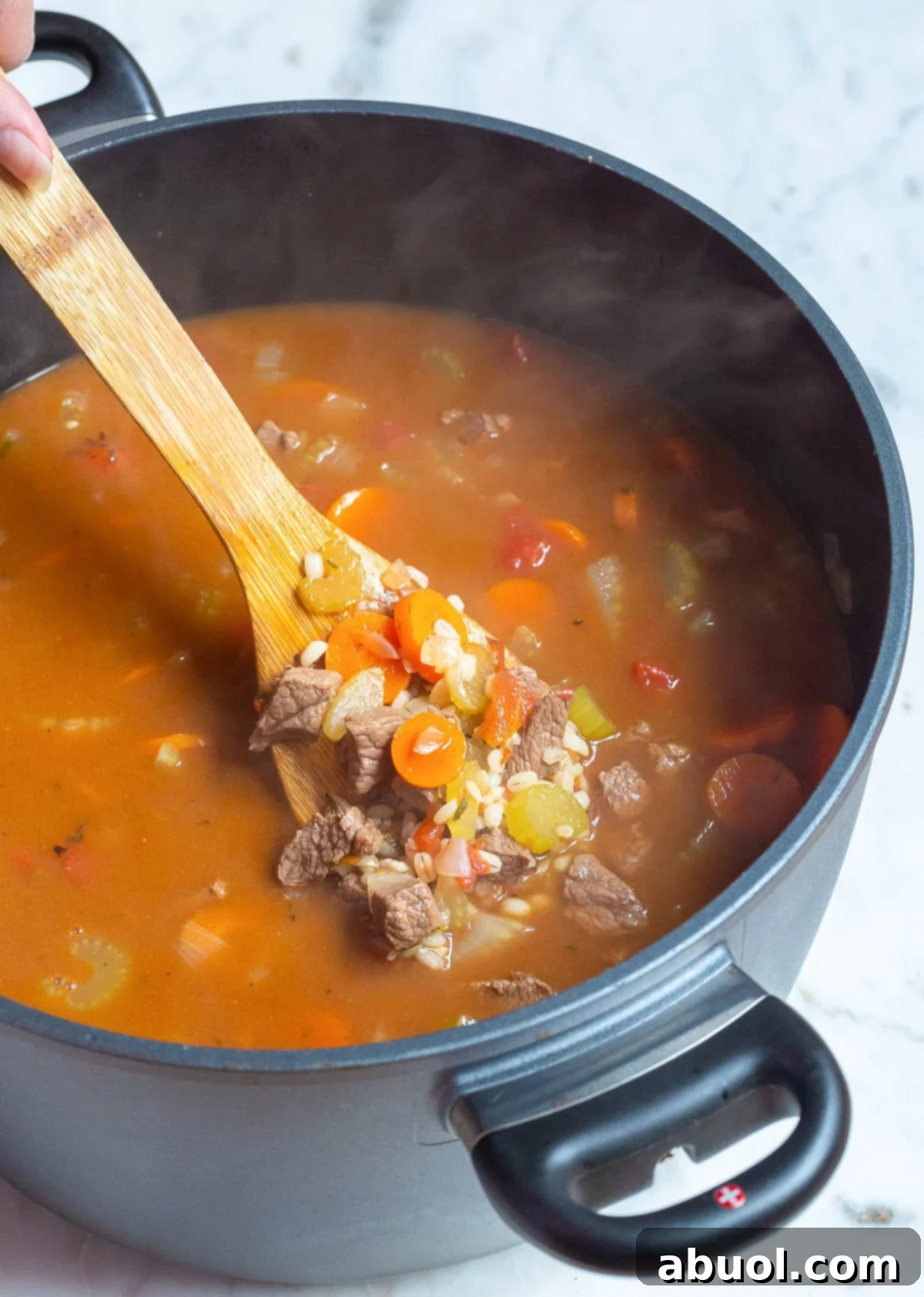 Hearty beef barley soup simmering in a large soup pot on the stove