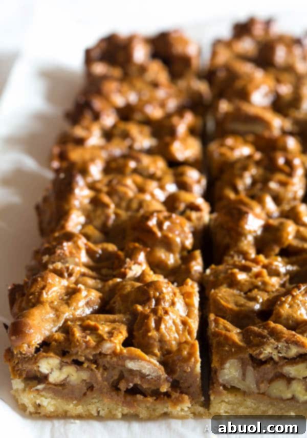 Caramel pecan slab pie on parchment paper, ready to be cut into individual bars.