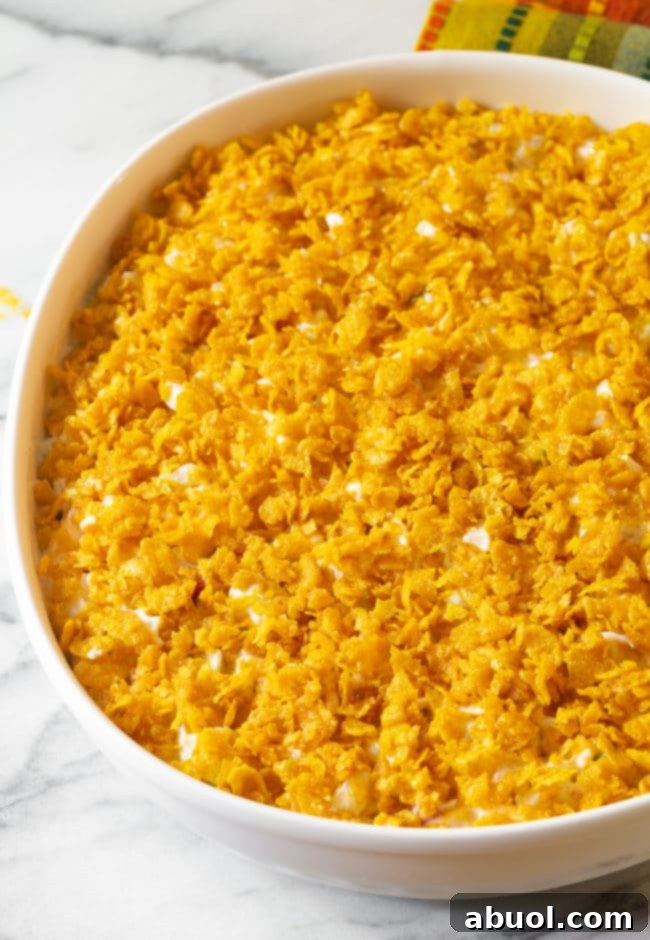 The potato mixture evenly topped with buttered, crushed cornflakes, preparing for baking.