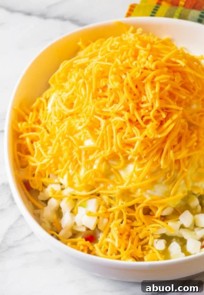 The potato mixture in a casserole dish, topped with a generous layer of shredded cheddar cheese.