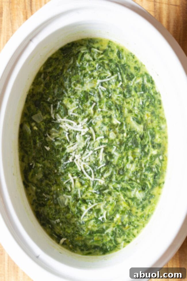 Crockpot with loaded creamy spinach topped with grated parmesan. 