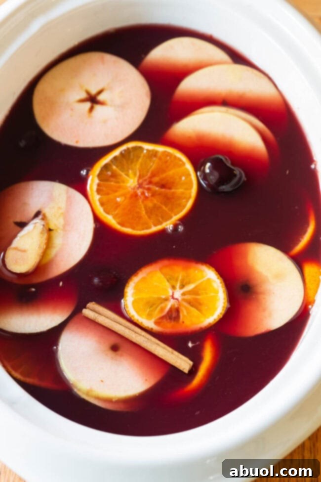 Ingredients for Mulled Wine (Wassail) laid out: red wine bottles, apple cider, orange juice, honey, various fruits, and whole spices.