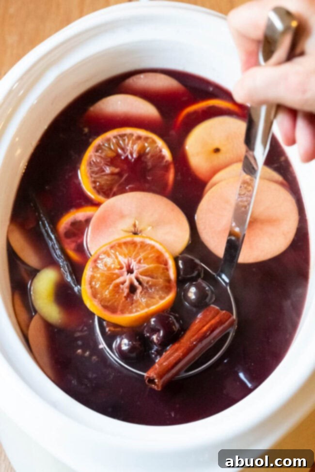 Mulled Wine (Hot Wassail) in a large crockpot, with vibrant fruit slices and spices beautifully arranged on top.