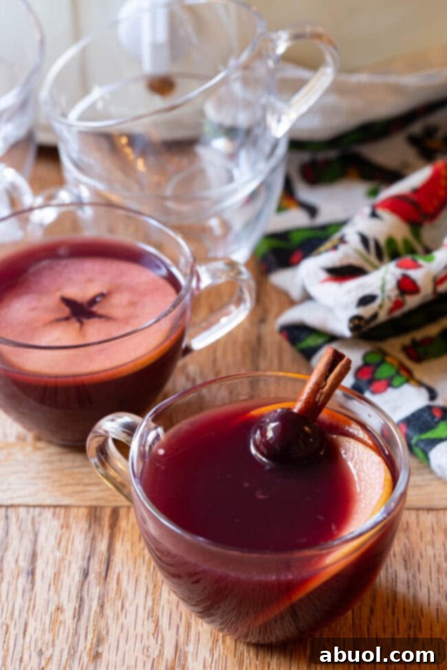 Christmas Drink - Mulled Wine Wassail Recipe served in small, clear glass mugs, garnished with orange slices and cinnamon sticks.