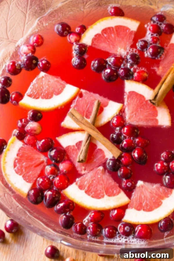 Holiday Punch #ASpicyPerspective Holiday Champagne Punch in a large punch bowl with fruit floating on top