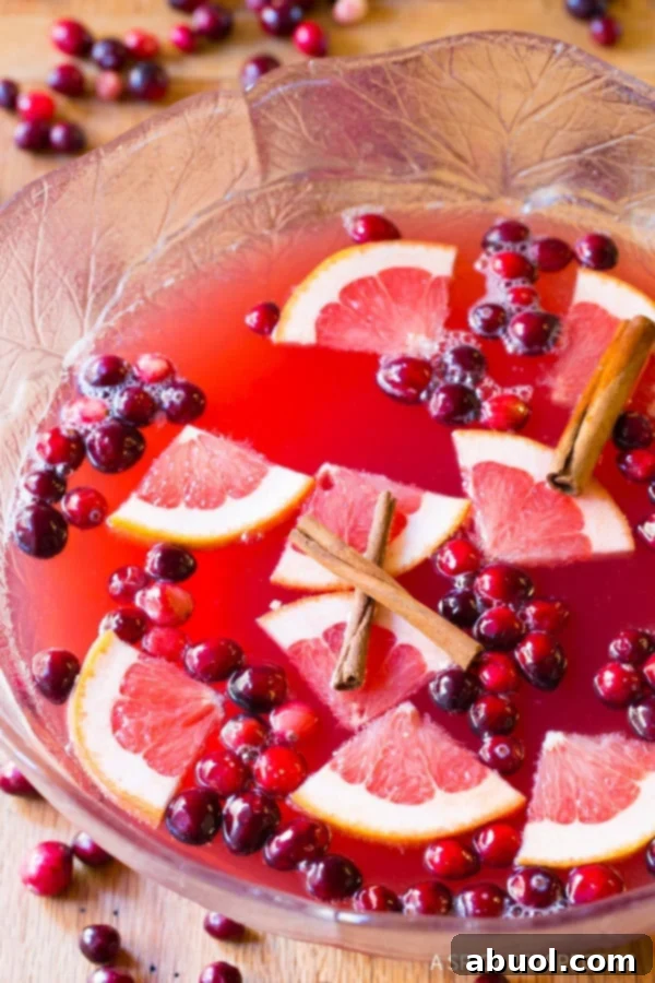 Christmas Punch #ASpicyPerspective Christmas Punch Recipe with champagne - overhead shot in large glass bowl - fruit and cinnamon sticks floating on top of the punch