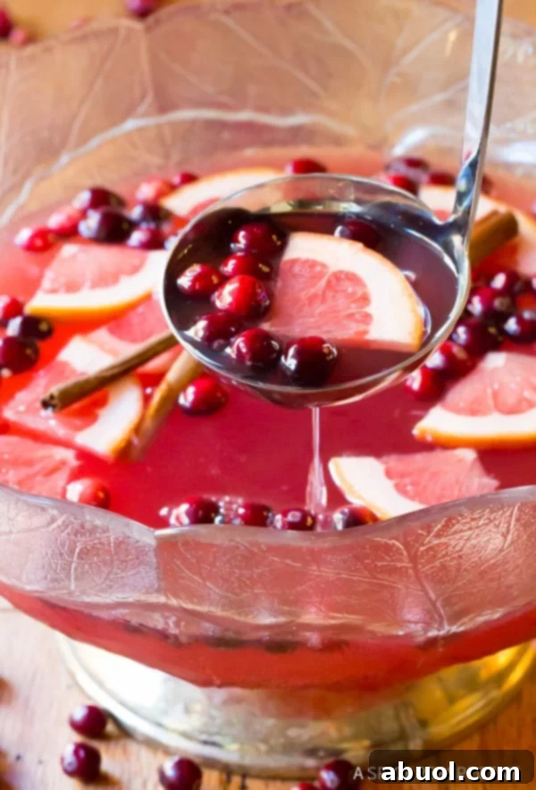 Christmas Punch #ASpicyPerspective Holiday Punch Recipe with champagne, scooped out of punch bowl with a ladle.