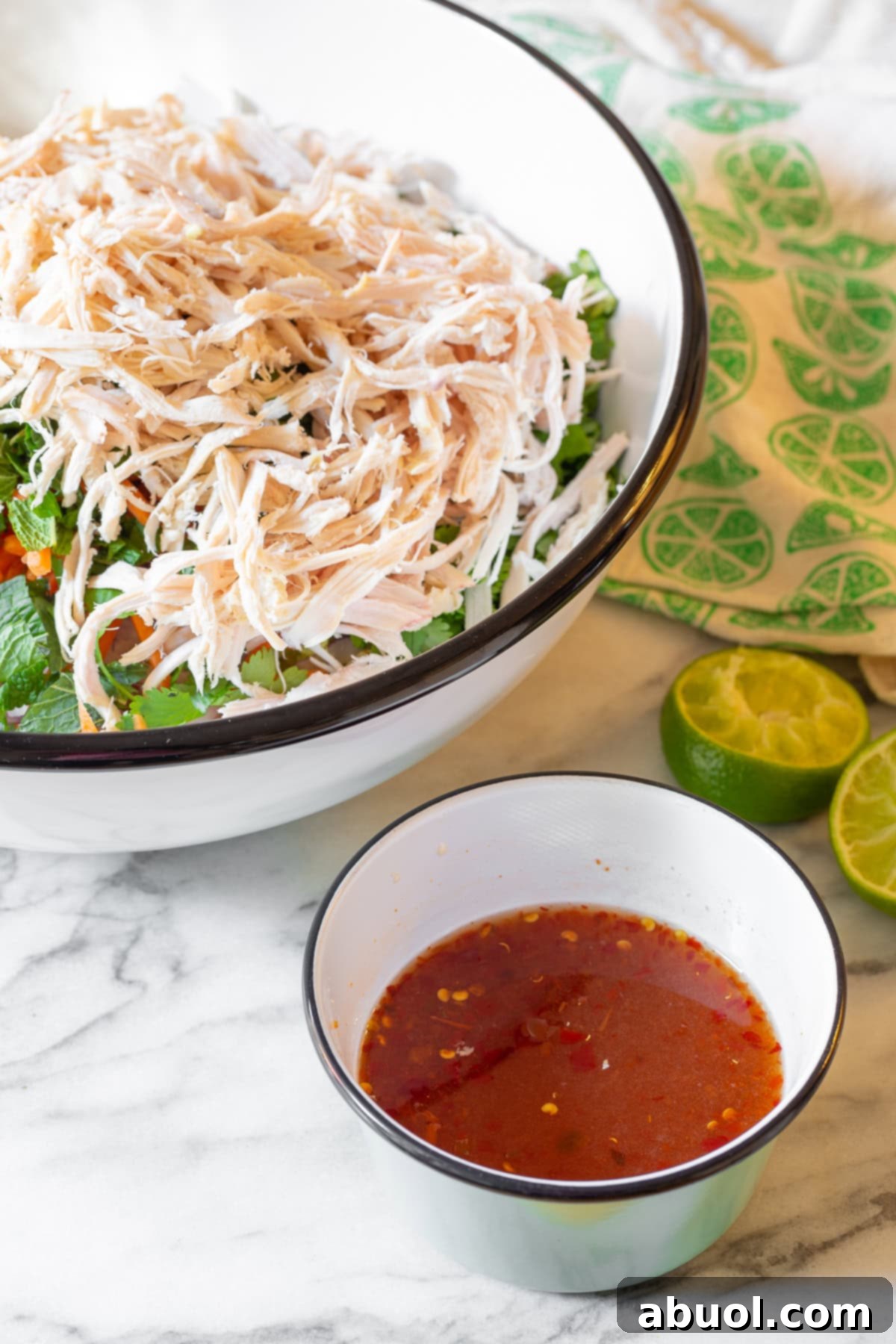 A vibrant cabbage salad in a large bowl, with a small bowl of clear, zesty dressing placed beside it, ready to be combined.