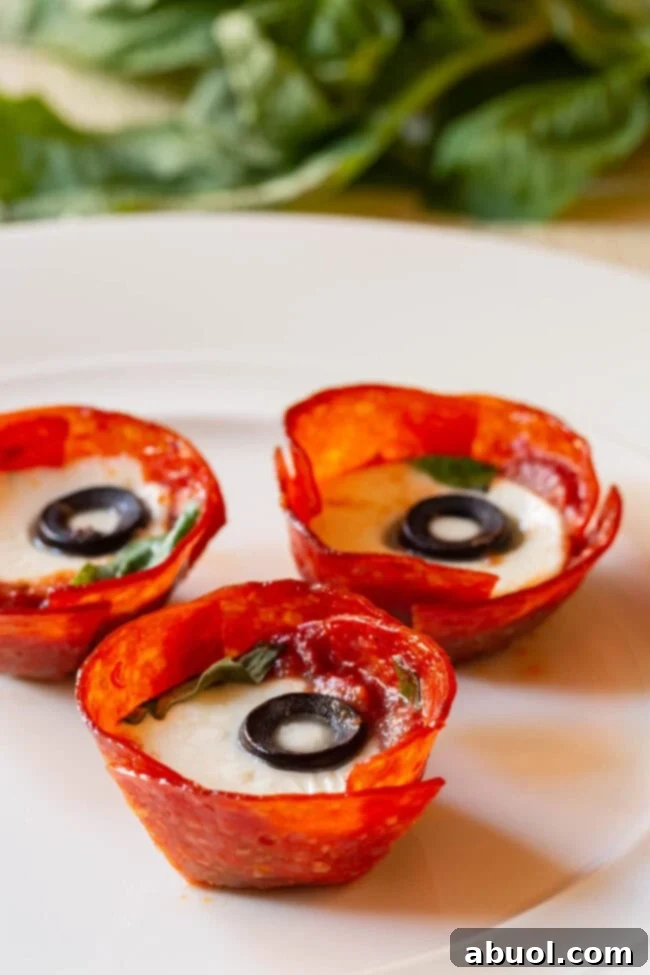 Keto Pepperoni Pizza Bites 6 Close-up of baked Low Carb Pepperoni Cups, showing melted mozzarella and black olives, ready to be enjoyed.