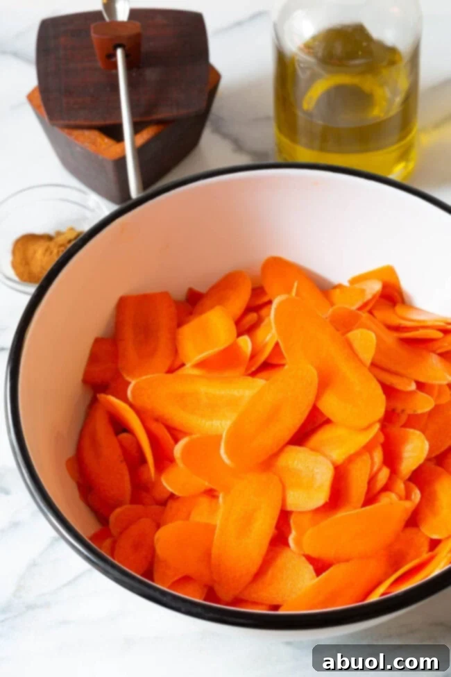 Crispy Baked Carrot Crisps 6 Thinly sliced carrot rounds in a bowl, ready for seasoning.