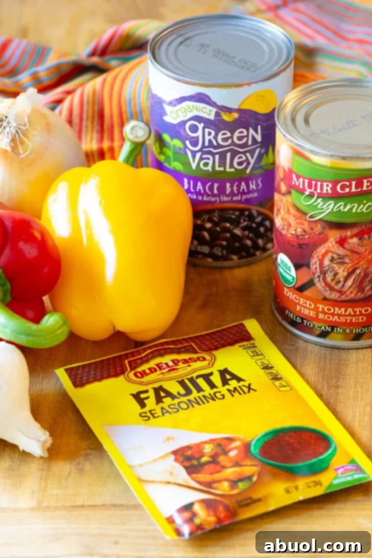 Ingredients for Mexican Chicken Soup: Packet of fajita seasoning mix, yellow and red bell peppers, can of diced tomatoes, can of black beans, and a bulb of garlic on a wood cutting board.