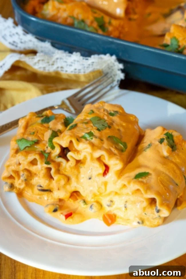 Three lasagna roll ups on a white plate with a silver fork. 