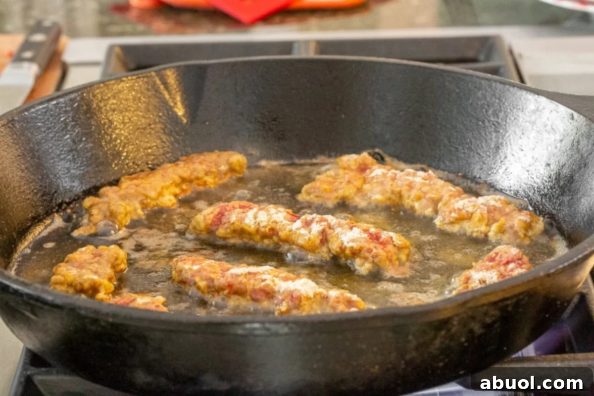 Crispy steak fingers sizzling in hot oil within a cast iron skillet, frying to a perfect golden brown.