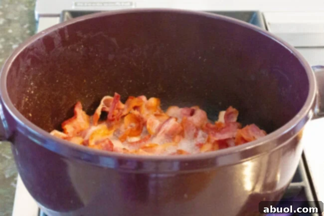 Preparing the Bacon for a Flavorful Irish Cabbage Dish Diced thick-cut bacon sizzling and rendering its fat in a large pot on the stovetop.