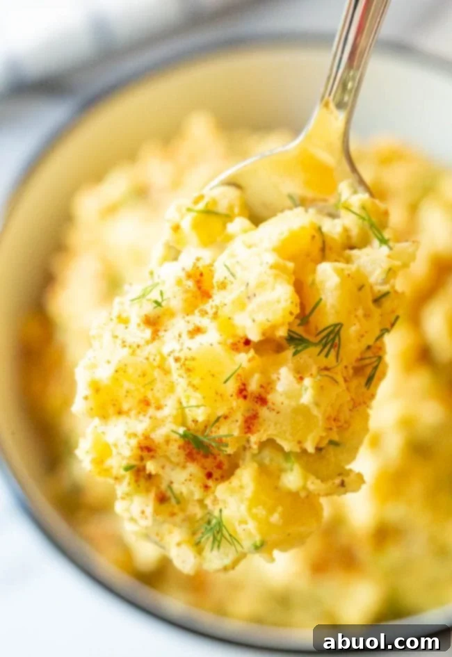 A spoonful of the family's secret creamy potato salad recipe being lifted from the bowl.