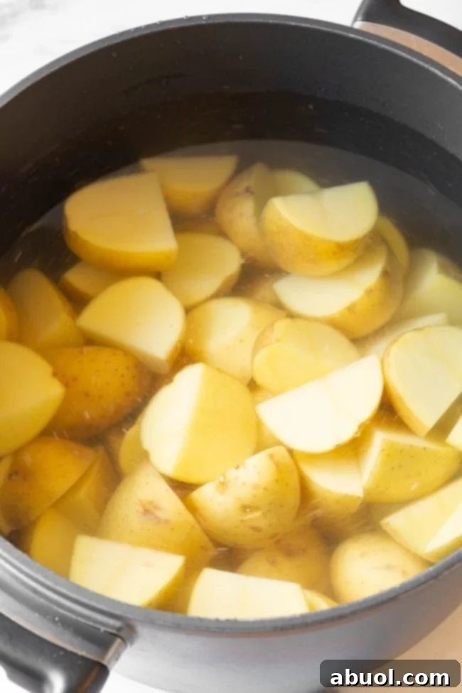 Potatoes boiling in a large saucepot, prepared for the creamy potato salad.
