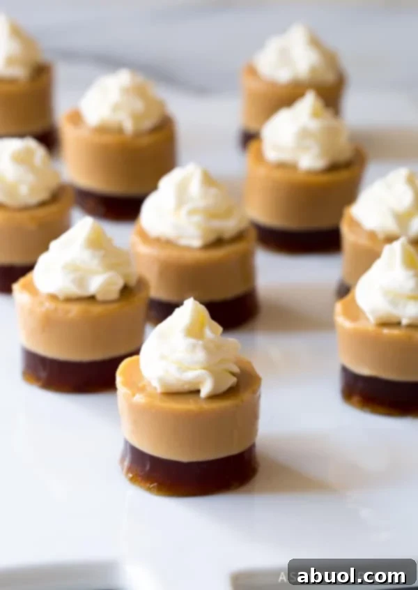 Layered Baileys Irish Cream and coffee jello shots, each adorned with a dollop of whipped cream, ready for serving.
