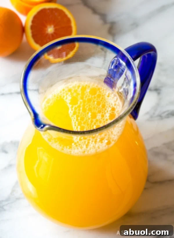A large glass pitcher filled with a beautifully vibrant Southern orangeade, ready to be served and enjoyed.